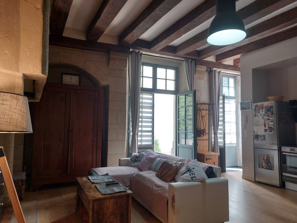 Un salon plein de charme avec cheminée et poutres apparentes dans un appartement à vendre dans le Vieux Tours